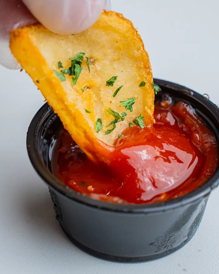 A potato scooper dipped in ketchup
